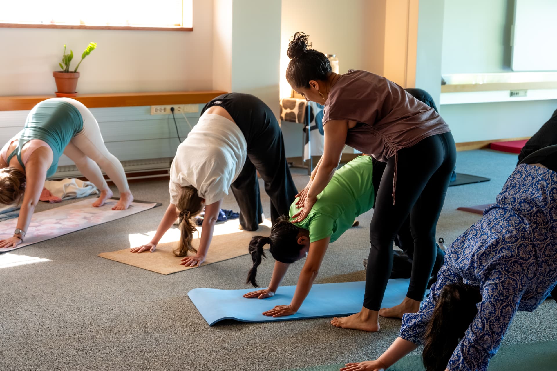 Uma offering a hands-on adjustment during a retreat yoga class